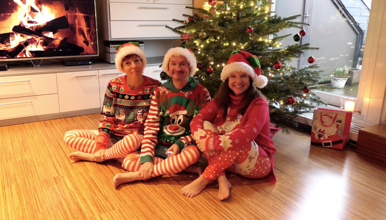 Jenni Karies, Andy Raaflaub und Kerstin Bredehorn sizen in Weihnachtskleidung vor einem geschmückten Tannenbaum