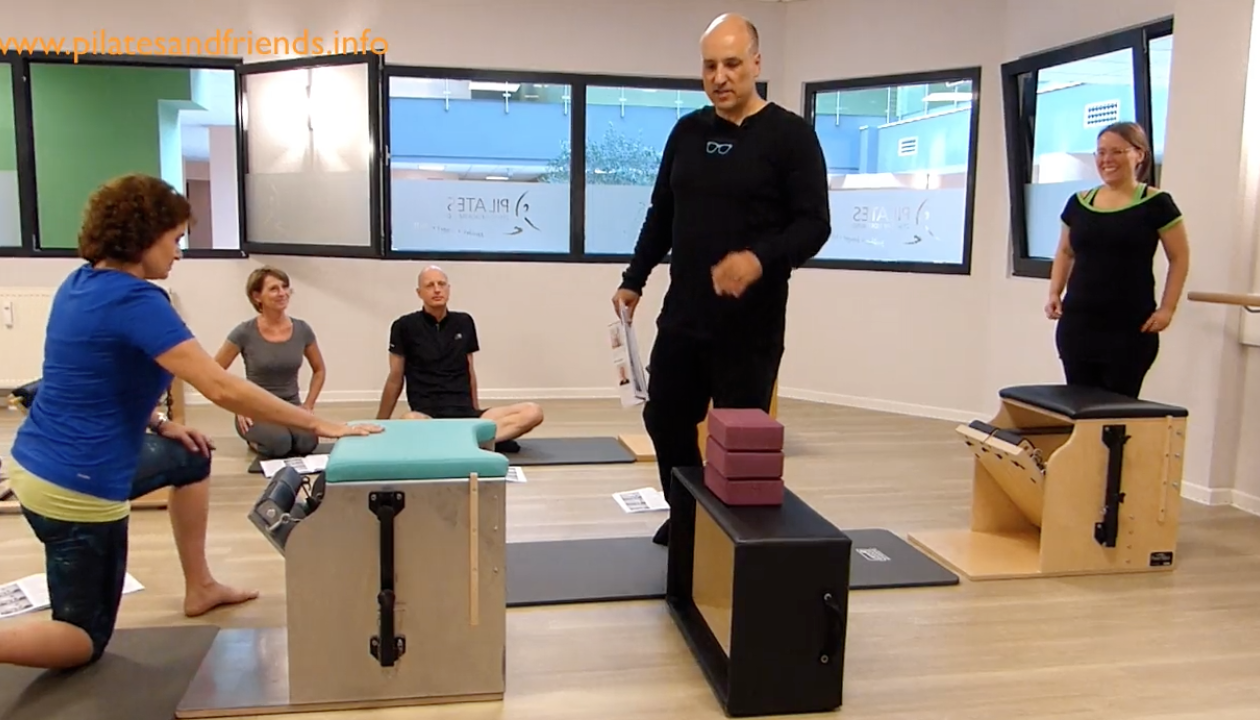 Reiner Grootenhuis steht hinter einer Box mit drei Yogablöcken. Vier Personen schauen zu ihm. 